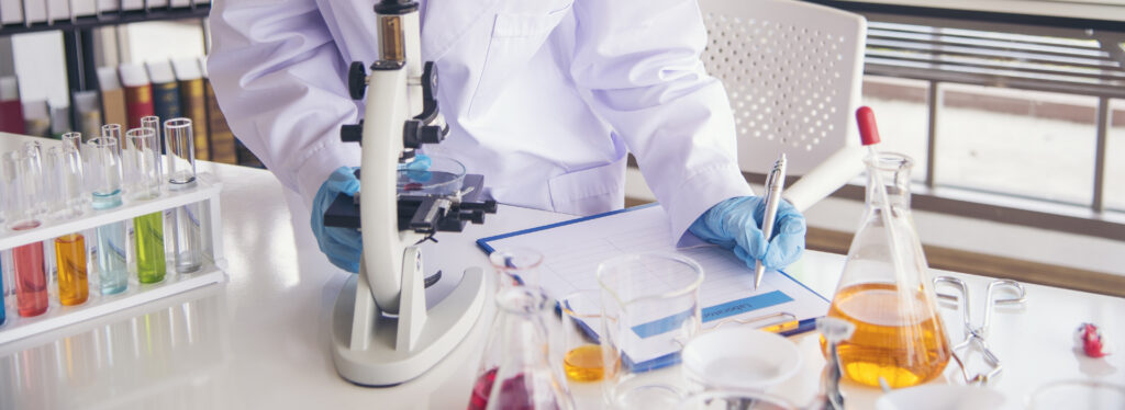 Banner Asian woman scientist hand write note research in medical lab look at science microscope. Asian Female technician laboratory using microscope with copy space. Banner Scientist chemistry